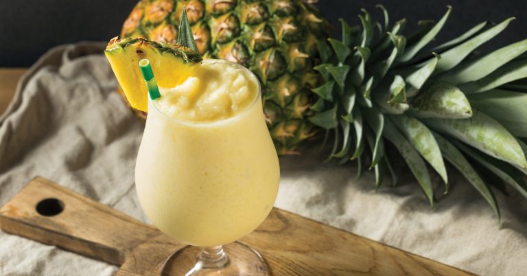 Glass of fresh pineapple colada smoothie garnished with pineapple and min